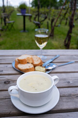 Lunch with homemade white asparagus soup and Dutch white wine served outdoor on green meadow with vineyard, asparagus and wine production farm in Netherlands