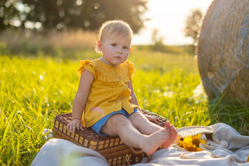 Little girl on a picnic at sunset lights in nature.