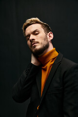 a man in an orange sweater and a jacket on a dark background blond portrait