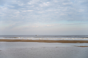 Low tide period on yellow sandy beach in small Belgian town De Haan or Le Coq sur mer, luxury vacation destination, summer holidays
