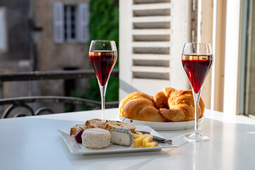 Drinking of Kir Royal,  French aperitif cocktail made  from creme de cassis topped with champagne, typically served in flute glass, with view on old French village
