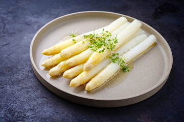 Modern style traditional steamed white asparagus with butter sauce hollandaise and cress served as...
