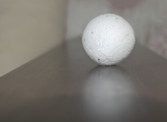 Closeup shot of a white ball on a gray surface