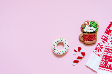 Donut, gingerbread and tea towel on pink background with copy space for your text, top view, flat lay