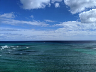 Fototapeta premium Aerial of Pacific Oeacn with waves rolling in and sail boat in the water