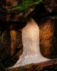 frozen water running out from a cave in the forest