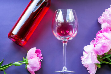 Rose wine in a large glass and beautiful peonies on a dark background. Creative summer composition. Happy Mother's Day, International Women's Day. Valentine's Day. Flat lay