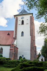 Fototapeta na wymiar Historic church with a bell tower with a clock in the city of Oborniki