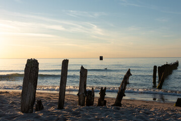 Old wooden breakwater on the beach during sunset. Mielno, Poland. Selective focus. 