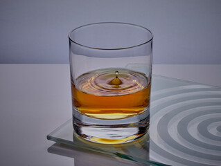 Glass of whisky,with a droplet splashing in to it.