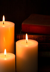 Three Pillar Candles Burning in a Dark Room with a Bible