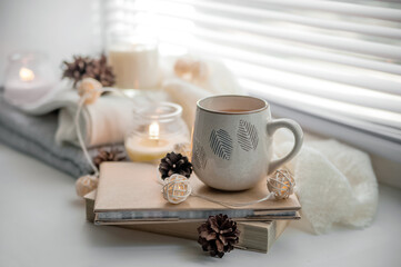 Obraz na płótnie Canvas ?ug of tea, white sweater and books with candles on windowsill. Cozy autumn concept...
