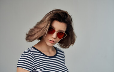 Naklejka premium blonde woman wearing sunglasses holds hand near face cropped studio view