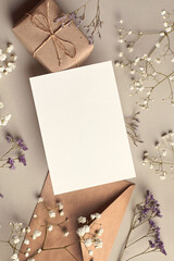 Invitation or greeting card mockup with gift box and dry flowers twigs