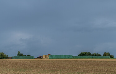 Fototapeta na wymiar Strohrollen lagern vor einer landwirtschaftlichen Lagerhalle