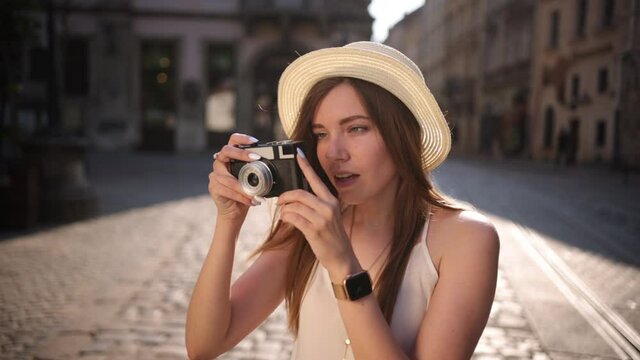 Tourist is exploring old city. Smiling, making photo on a retro camera. Outdoor