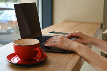 The girl sits at the table and works at a laptop and a smartphone. Remote work from home, cafe, business space. Business lady at work. Business background. Home office