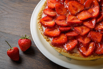 Homemade strawberry pie with syrup on a ceramic platter.