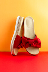 Two bright red flip flops stand against a beautiful red-orange background