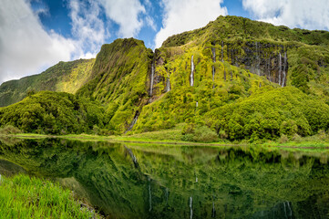 Azores scenic landscape, Flores island. Iconic lagoon with over 20 separate waterfalls on a single rockface, flowing into lake Alagoinha. Best travel destination in Portugal, amazing vacations place.