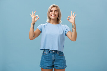I got you covered. Enthusiastic attractive and energized female blonde with tattooed arms showing...