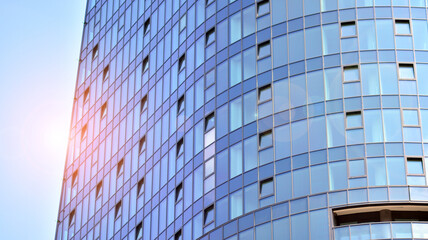 Glass and steel. Mirrored facade of modern office building with sunbeams glare reflection