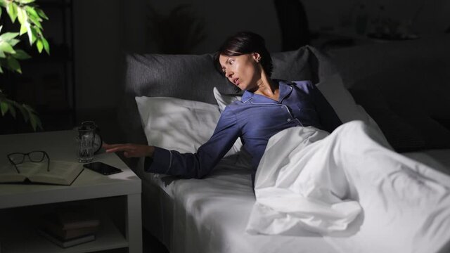 Mature woman in pajamas jumping out of bed because of being late in morning. Overslept lady at home. Not in time concept.
