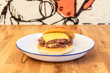 Double beef burger with melted cheddar cheese and brioche bread on a white enamel plate