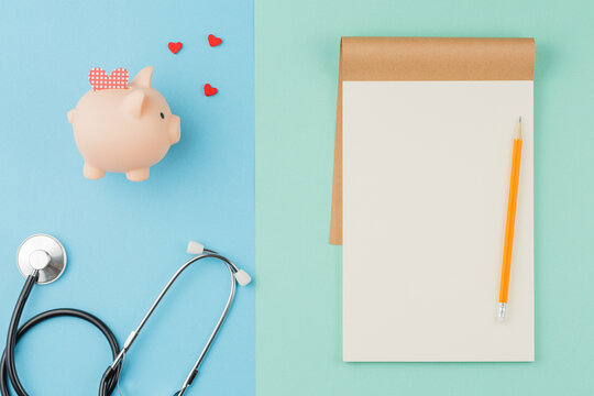 Piggy bank with stethoscope and notebook with pen.