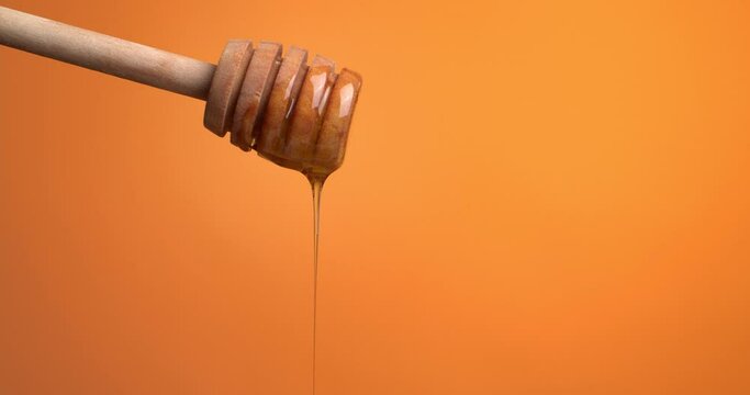 Sweet honey dripping from dipper against color background