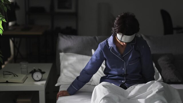 Middle Aged Woman In Sleep Mask And Pajamas Unable To Wake Up In Bed. Early Morning Awakening. Exhaustion And No Energy Concept.