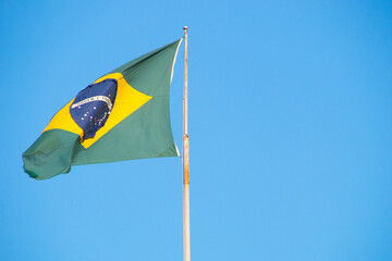 Flag of Brazil outdoors with a beautiful blue sky in the background in Rio de Janeiro.