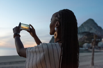 Black female tourist shooting sunset sky
