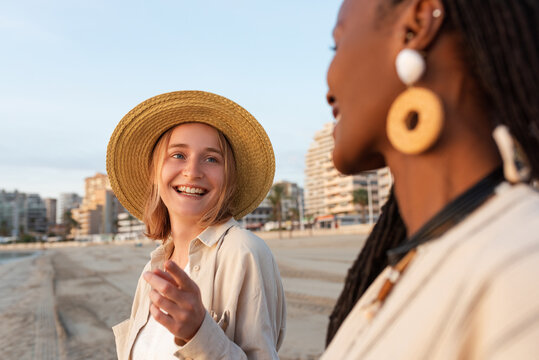 Happy woman talking with black female friend on beach