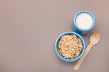 Barley Porridge in a ceramic bowl. Healthy breakfast porridge oats on a beige table. Clean eating food.
