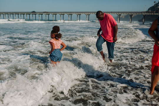 Father and daughter wade in ocean