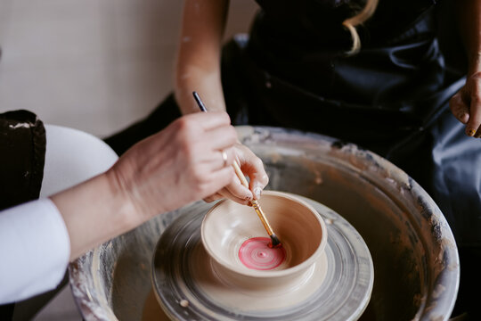 Artists drawing elements on handmade cup in workshop 