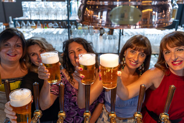 group of mature women is drinking beer in a pub in front of a beer tap