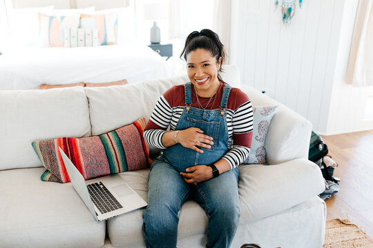A pregnant woman working on a laptop 