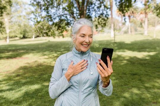 Older Woman Holds Her Heart While Talking On The Phone