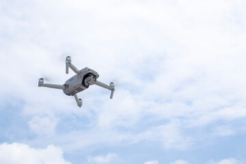 The drone flies in the blue cloudy sky. New technologies for photo and video shooting.