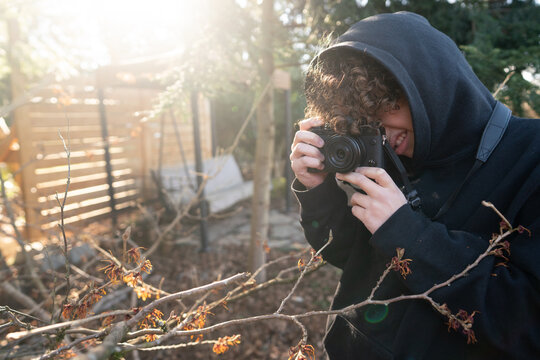 Boy with camera taking photo of tree blossom
