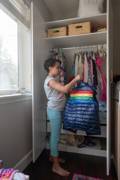 Girl hangs rainbow vest in closet