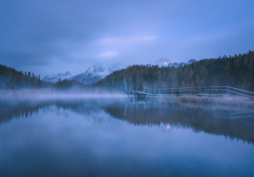 Misty morning landscape at the alpine lake.