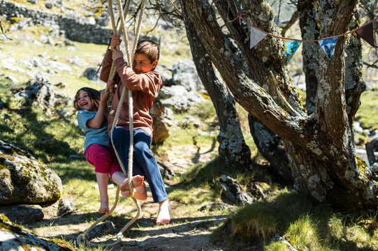 Children having fun riding on a makeshift swing at field