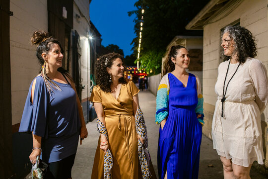 Cheerful girlfriends talking during festive event in town
