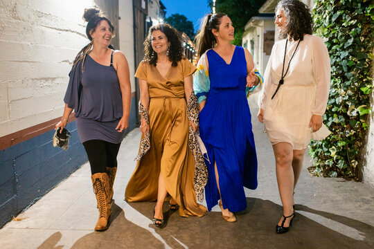 Cheerful girlfriends talking during festive event in town