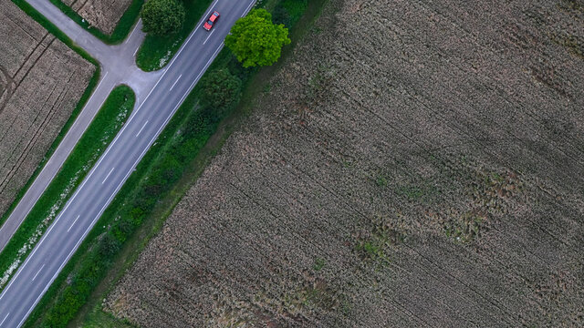Rotes Auto auf der Landstra&szlig;e neben Fahrradweg und landwirtschaftlichen Feldern - Luftaufnahme Navigation vom Satellit.