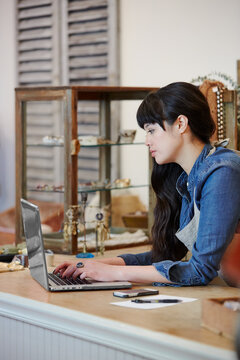 Business owner using laptop on counter of store