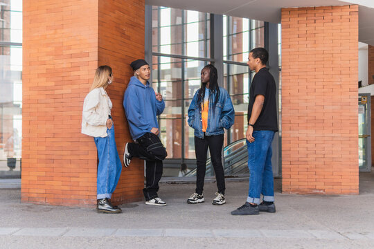 Group of diverse friends talking near building in city